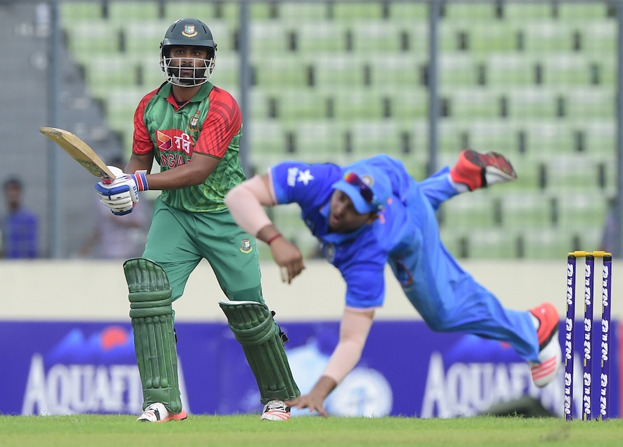 Bangladesh cricketer Tamim Iqbal (L) plays a shot as Indian cricketer Suresh Raina (R) tries to catch the ball during the first one day international (ODI) cricket match between Bangladesh and India at The Sher-e-Bangla National Cricket Stadium in Dhaka on June 18, 2015. AFP PHOTO/Munir uz ZAMAN        (Photo credit should read MUNIR UZ ZAMAN/AFP/Getty Images)